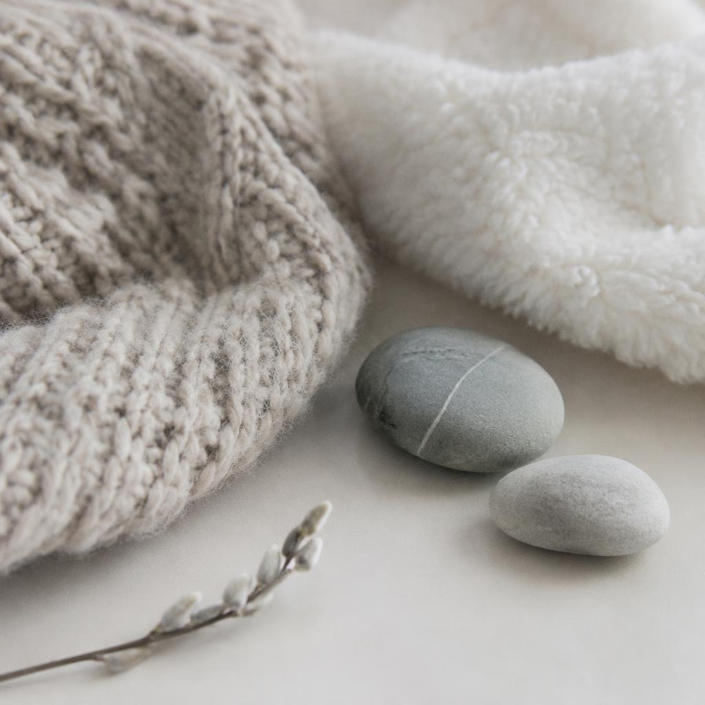 Soft knitted wool, smooth stones, and fluffy fabric in gentle light